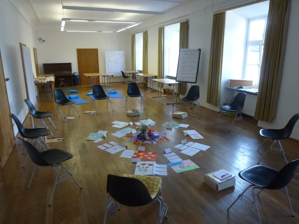Seminarraum mit Stuhlkreis und Bildkarten in der Mitte auf dem Holzboden